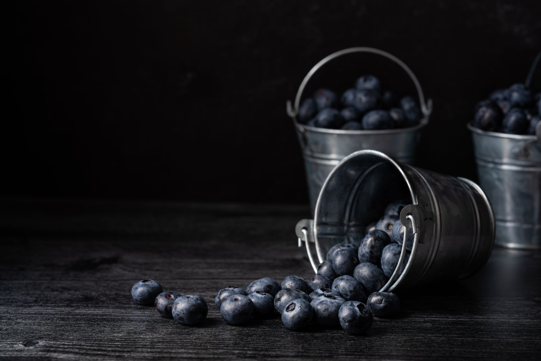 Blueberries spilling from small metal pails
