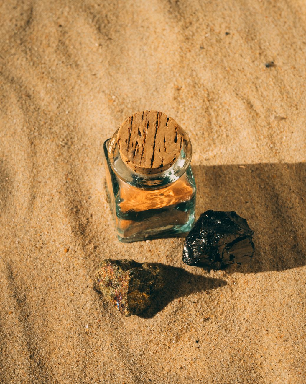 Small sealed shilajit jar resting in sunlit sand